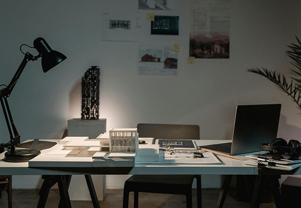 A group of professionally dressed men and women sitting at a conference table with notes and laptops.