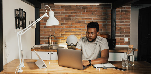 A group of professionally dressed men and women sitting at a conference table with notes and laptops.