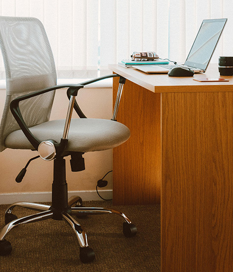 A desk with documents and laptop in a dimly lit room with architectural posters on the wall.