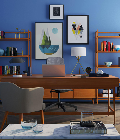 A desk with documents and laptop in a dimly lit room with architectural posters on the wall.
